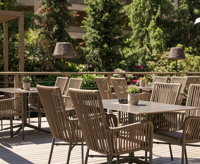 Terrasse im Hotel Feldhof in Naturns Leere Holzterrasse mit Tischen, Stühlen und Blick ins Grün im Feldhof DolceVita Resort.