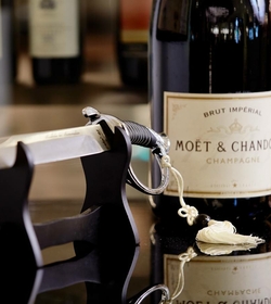 Eine Moët & Chandon Champagnerflasche steht neben einem Flaschenhalter auf einer Spiegeloberfläche.