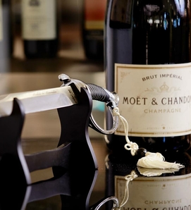 Eine Moët & Chandon Champagnerflasche steht neben einem Flaschenhalter auf einer Spiegeloberfläche.