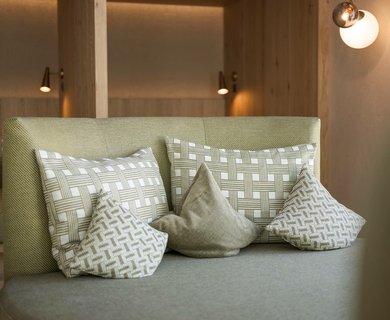 Gemütliche Hotel-Lounge mit dekorativen Kissen Eine gepolsterte Sitzbank mit mehreren dekorativen Kissen steht in einer warm beleuchteten Hotel-Lounge.