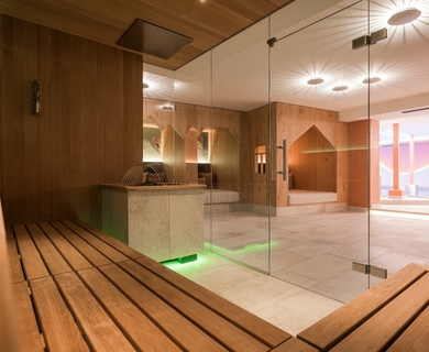 Sauna und Ruhebereich im Feldhof DolceVita Resort Eine moderne Sauna mit Holzliegen und Glasfront neben einem hellen Ruhebereich.