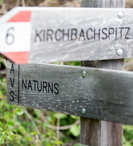 Un segnavia in legno indica Kirchbachspitze e Naturns.