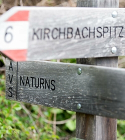 Un segnavia in legno indica Kirchbachspitze e Naturns.