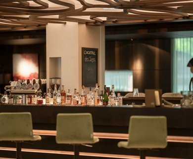 Hotelbar im Feldhof DolceVita Resort Eine moderne Hotelbar mit Getränken und grünen Barhockern im Feldhof DolceVita Resort.