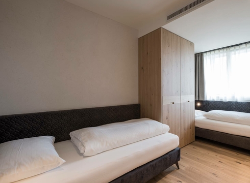 Suite Nature con letti singoli luminosi al Feldhof Una camera da letto semplice della Suite Nature con due letti singoli, armadio in legno e luce naturale.