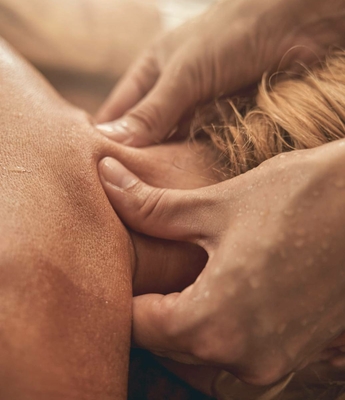 Massage im Spa des Feldhof in Naturns Hände massieren den Nacken einer Person bei einer Wellnessbehandlung im Spa.