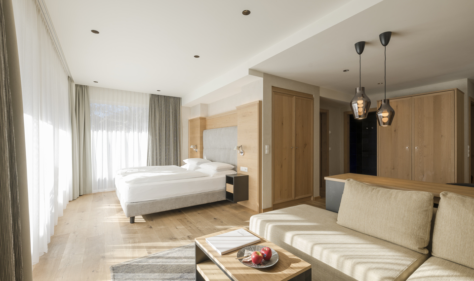 Suite mit Balkon im Feldhof DolceVita Resort Helle Suite mit Bett, Sofa und Balkonblick im Feldhof DolceVita Resort.