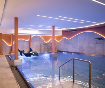 Ein ruhiger Innenpool mit Liegeflächen und warm beleuchteten Wänden im Wellnessbereich.