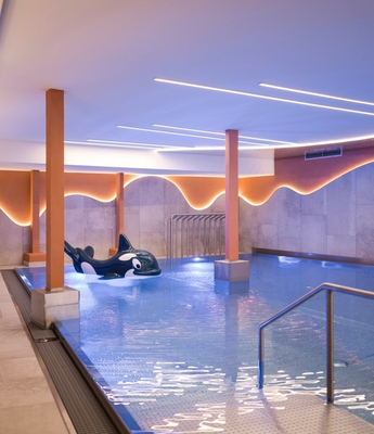 Wellnesspool im Adults Only Spa in Naturns Ein ruhiger Innenpool mit Liegeflächen und warm beleuchteten Wänden im Wellnessbereich.