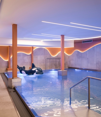 Wellnesspool im Adults Only Spa in Naturns Ein ruhiger Innenpool mit Liegeflächen und warm beleuchteten Wänden im Wellnessbereich.