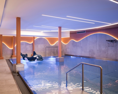 Ein ruhiger Innenpool mit Liegeflächen und warm beleuchteten Wänden im Wellnessbereich.