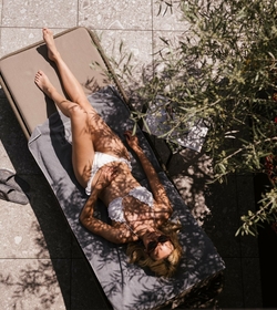 Eine Frau liegt entspannt auf einer Liege im Adults Only Spa, teilweise von Pflanzenschatten bedeckt.
