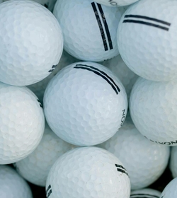 Several white golf balls are piled closely together and fill the entire frame.