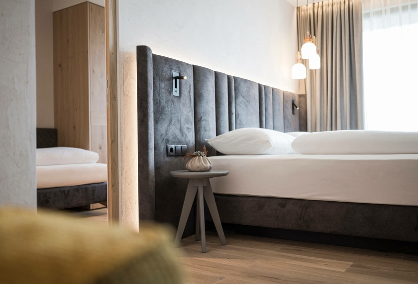 Camera suite al Feldhof con design moderno Una camera da letto moderna con letto matrimoniale, tavolino e tende al Feldhof.