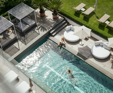 Poolbereich mit Liegen im Feldhof DolceVita Resort Ein Außenpool mit Sonnenschirmen, Liegen und Holzdeck im grünen Garten des Feldhof DolceVita Resort.
