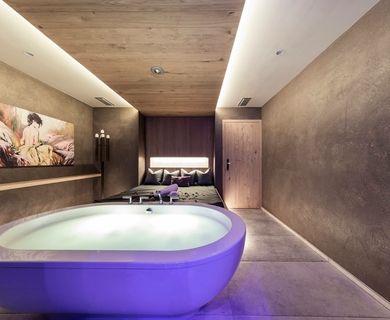 Wellnesssuite mit Whirlpool im Feldhof Eine moderne Wellnesssuite mit freistehendem Whirlpool, Doppelbett und warmen Naturtönen im Feldhof DolceVita Resort.