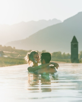 Infinity Pool mit Bergblick im Feldhof Ein Paar steht im Infinity-Pool mit Blick auf die Berge im warmen Licht der Abendsonne.