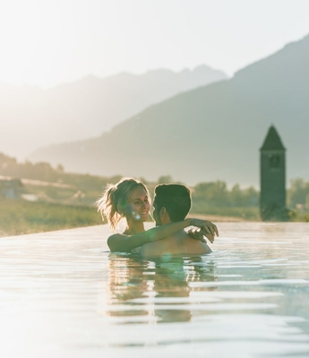 Piscina a sfioro con vista sulle montagne al Feldhof Una coppia è nella piscina a sfioro con vista sulle montagne, nella luce calda della sera.