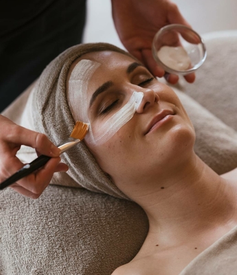 Beauty Treatment im Spa des Feldhofs Eine Frau erhält im Spa eine Gesichtsbehandlung, während die Creme mit einem Pinsel aufgetragen wird.