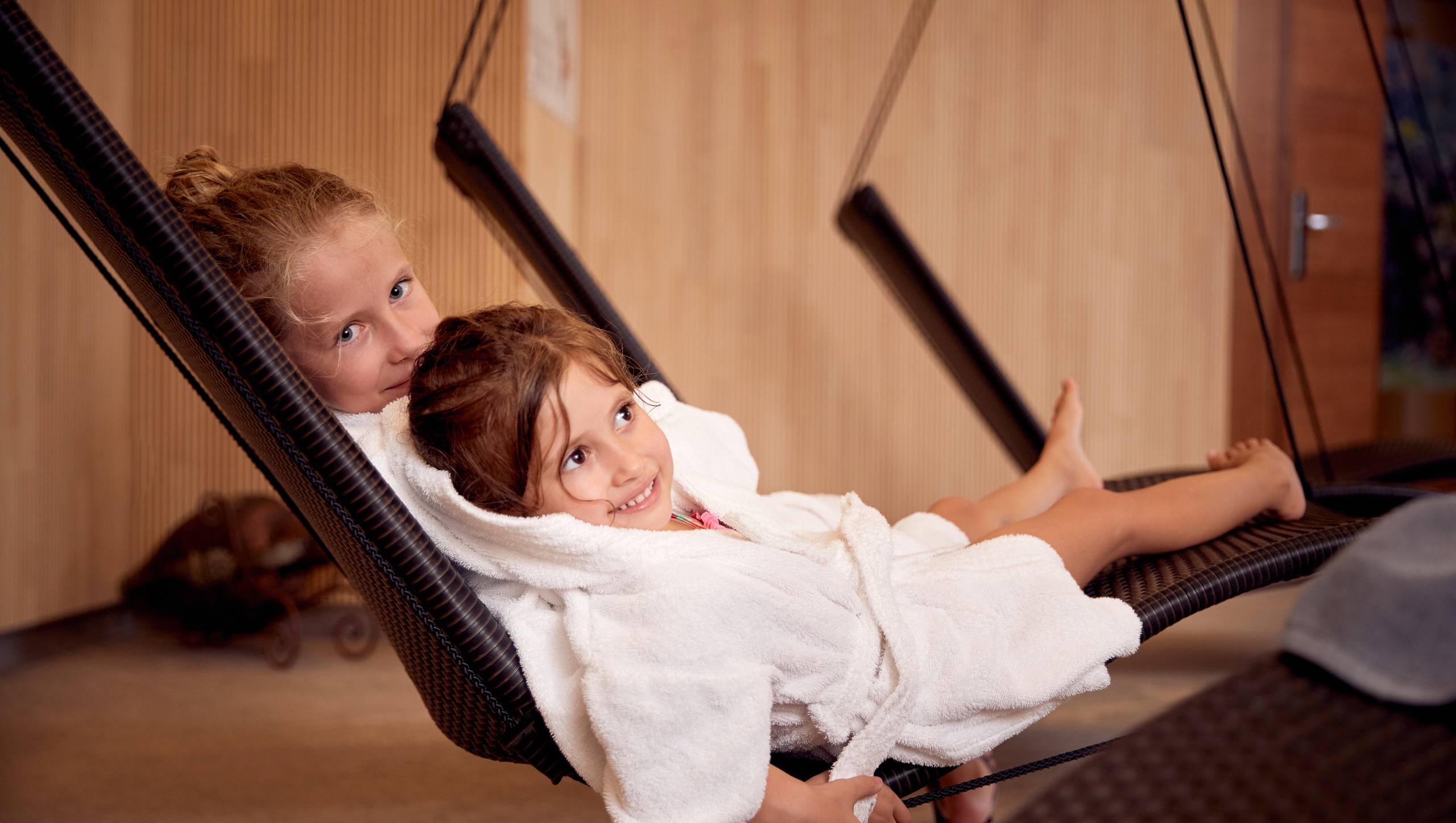 Zwei Kinder liegen entspannt in Hängesesseln im Family Spa.